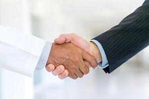 Man in lab coat and man in suit shaking hands