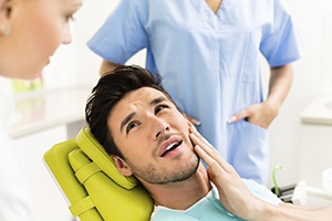 Man in dental chair holding cheek