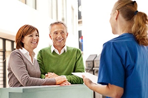 Smiling older couple talks to dental team member