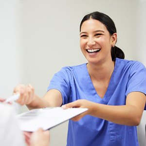 Woman handing a patient their dental insurance form