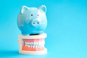 Blue piggy bank sitting on top of a dental model