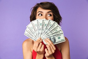 Woman covering her face with a fan of bills