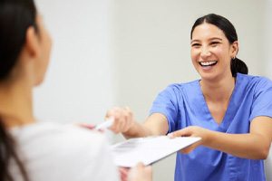 Dental team member giving clipboard to patient