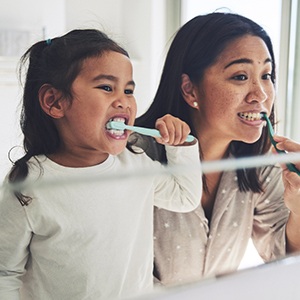 A mother and daughter brushing their teeth.