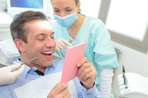 Patient with dental bridge in Lewisville looking in dental mirror
