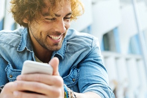 Closeup of man smiling while holding phone outside