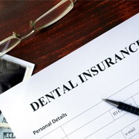 Insurance paperwork and dental X-ray on wooden desk  
