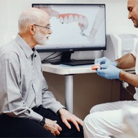Denture dentist in Lewisville showing model teeth to patient 