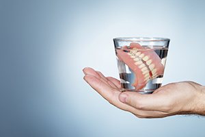 Patient holding dentures in glass