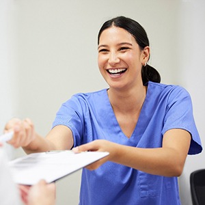 a front desk dental worker handing patients forms