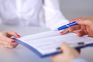 a person handing a patient forms on a clipboard