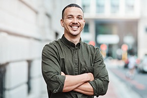 a smiling man wearing a button down shirt with his arms crossed