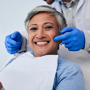 Senior female patient smiling with dentist standing behind her