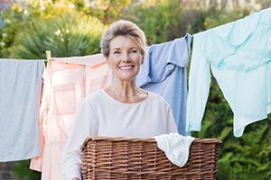 Senior woman doing laundry outside and smiling