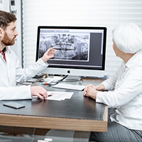 Implant dentist in Lewisville pointing at an X-ray with patient