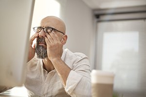 Tired man with hands over eyes