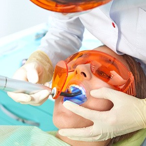 Dentist using curing light during dental filling procedure