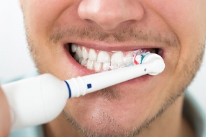 man with facial hair using electric toothbrush