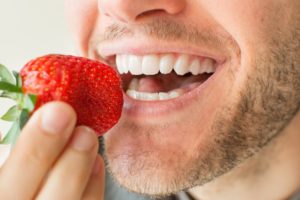 A man eating a strawberry.