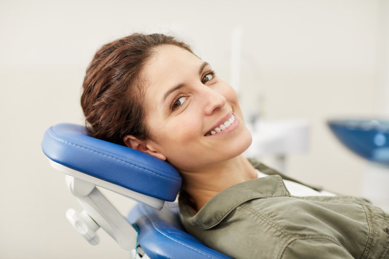 a woman smiling while sitting in the dentist’s chair