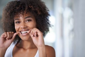 young woman flossing to prevent needing emergency dentist in Lewisville 