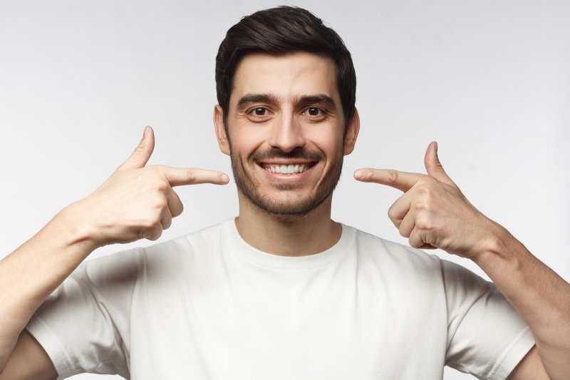 man smiling and pointing to gray teeth