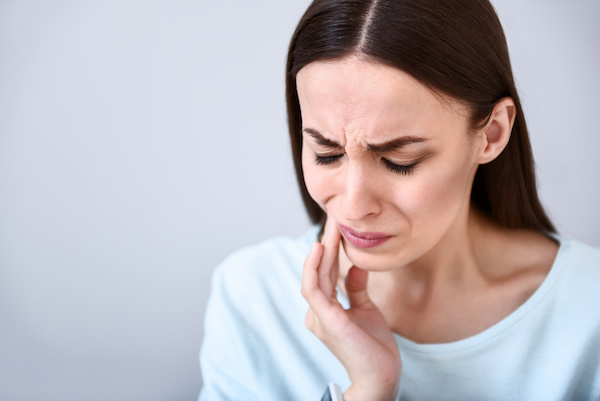 woman with a toothache, touching cheek, white background