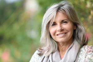 Mature woman smiling with dental implants after menopause