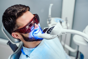 Man in dental chair having teeth professionally whitened