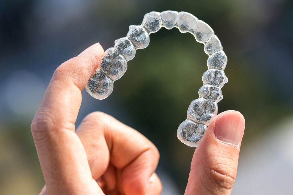 Fingers holding a single Invisalign tray