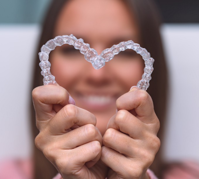 Woman holding clear aligners in the shape of a heart