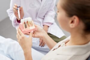 Dentist showing patient dental implant model. 
