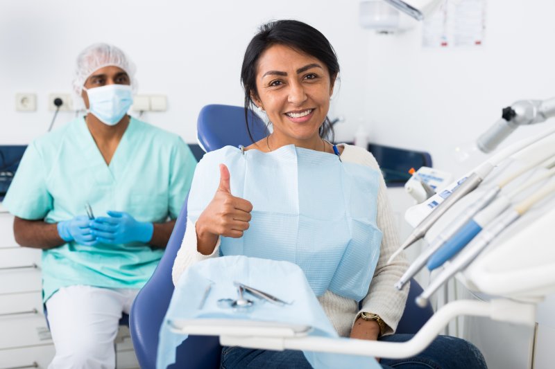 Patient giving thumbs-up at dentist after root canal retreatment