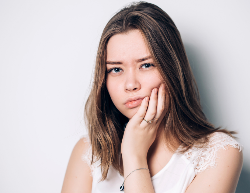 Girl holding jaw, frowning
