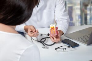 Dentist consulting with patient holding model of infected tooth.